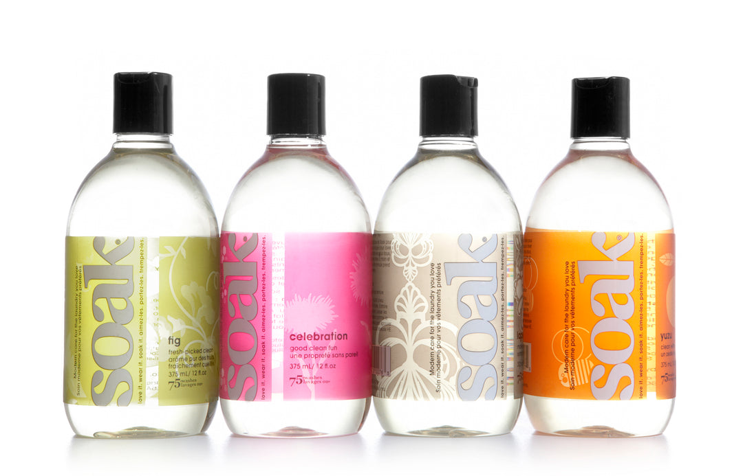Four clear plastic bottles with green, pink, brown and orange labels with the word Soak.