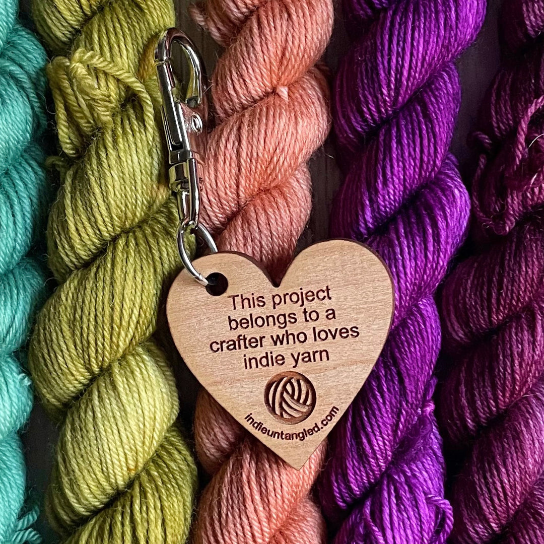 A heart-shaped wooden fob engraved with the words This project belongs to a crafter who loves indie yarn, a yarn ball and indieuntangled.com.