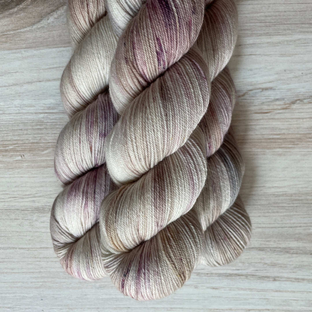 Cream yarn speckled with purple.